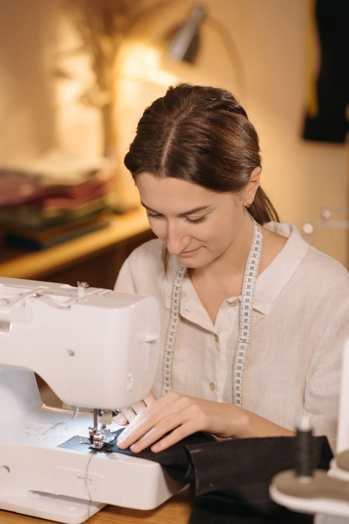 A talented seamstress concentrating on sewing with a modern machine in a cozy workspace.