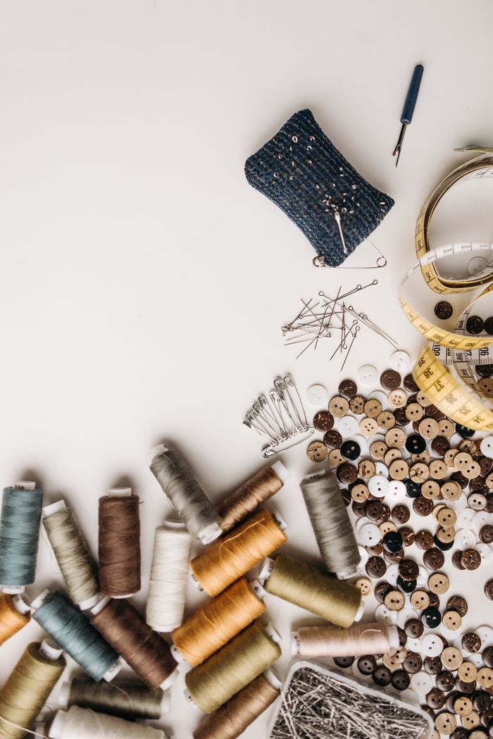 The Art of Drawing Readers In: Your attractive post title goes here Artistic flat lay of sewing essentials including threads, buttons, and pins on a white surface.
